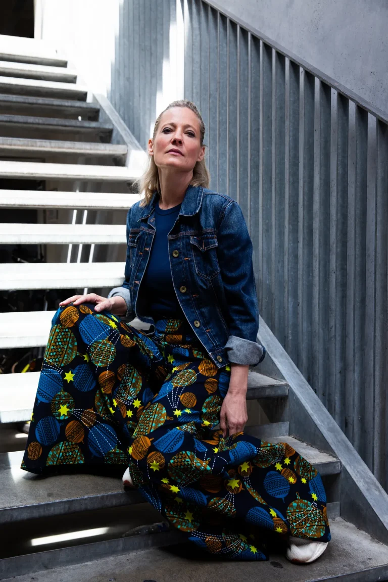 Frau sitzt auf Metalltreppe mit Musterhose