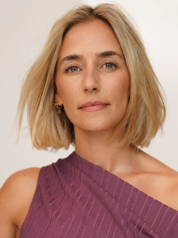 Porträt einer blonden Frau im lilafarbenen One-Shoulder-Top