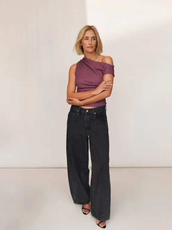 Frau im lila One-Shoulder-Top und schwarzer Jeans