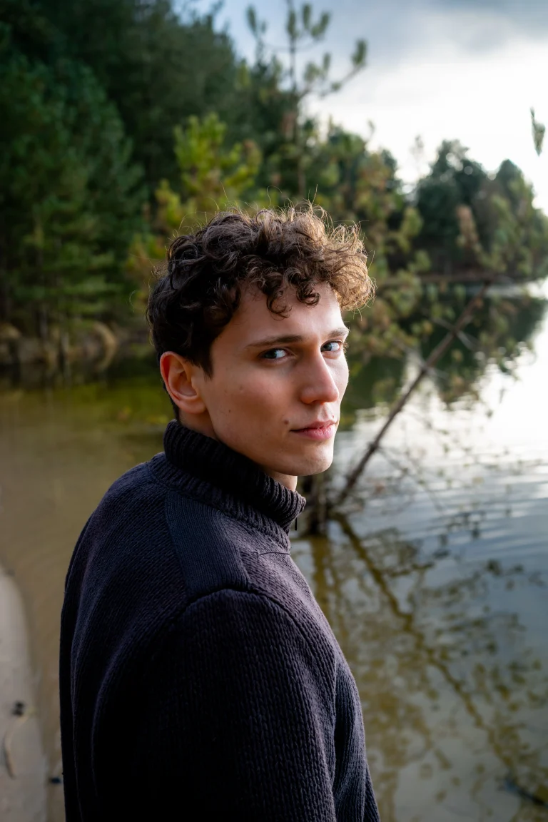 Junger Mann am See blickt über Schulter