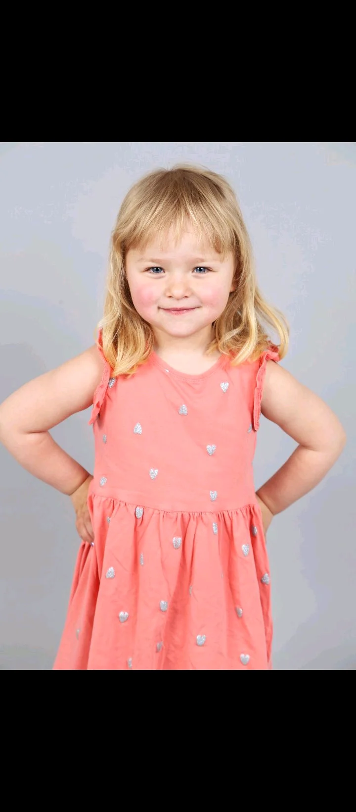 Blondes Mädchen im rosa Kleid mit Herzen