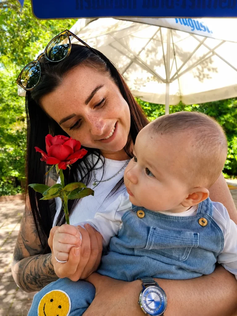 Frau mit Baby und roter Rose im Park