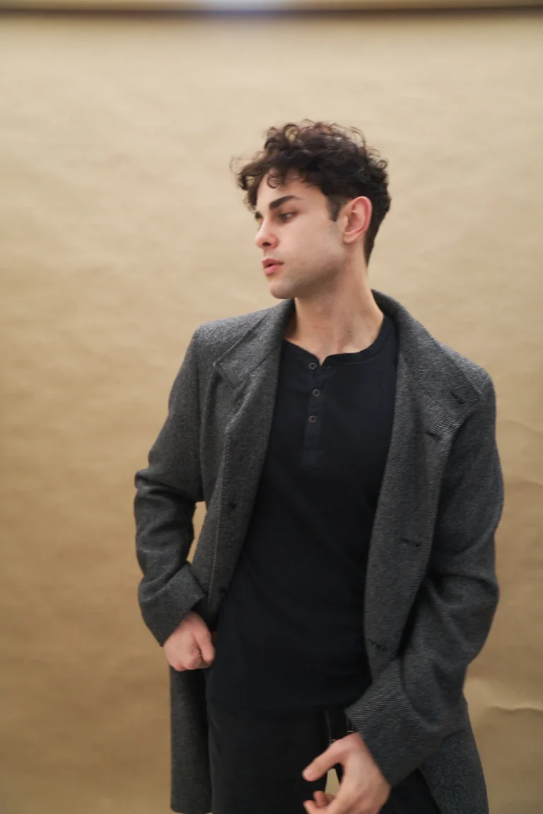 Junger Mann mit Locken im grauen Mantel