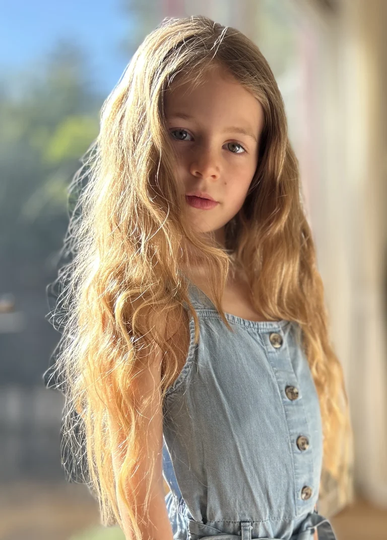 Blondes Mädchen im Sonnenlicht am Fenster