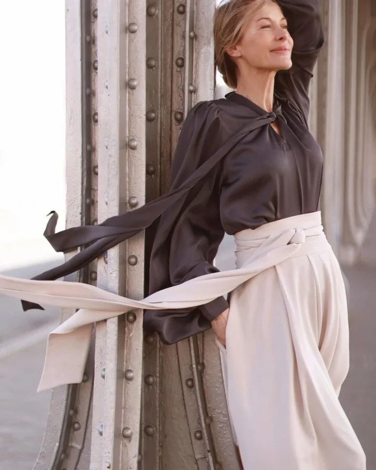 Elegante Frau mit fließender Bluse an Metallpfeiler