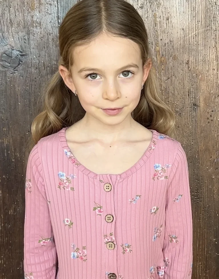 Mädchen mit rosa Kleid vor Holzwand