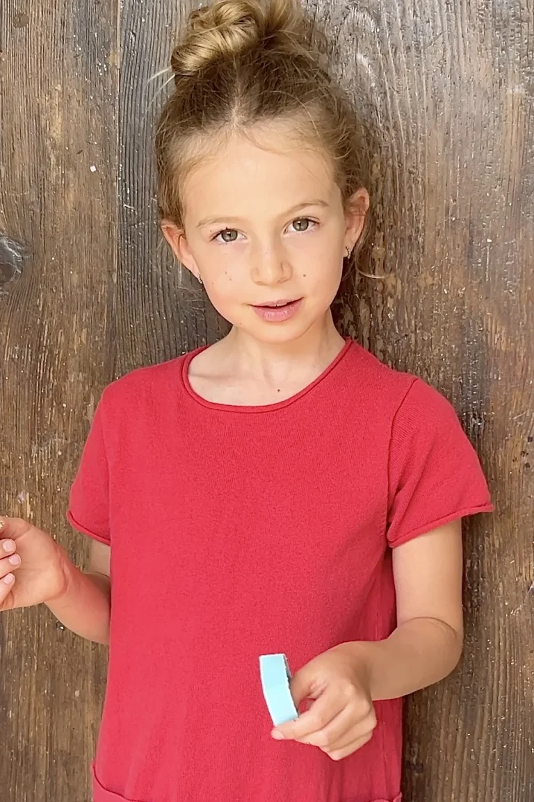Mädchen im roten Shirt vor Holzwand