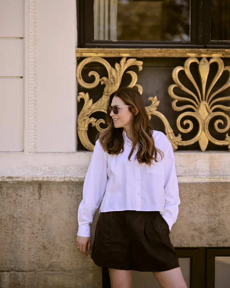 Frau mit Sonnenbrille vor verzierter Goldfassade