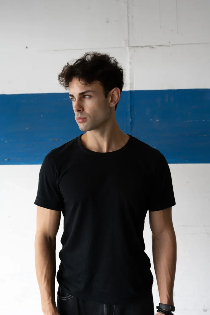 Mann im schwarzen T-Shirt vor blau-weißer Wand