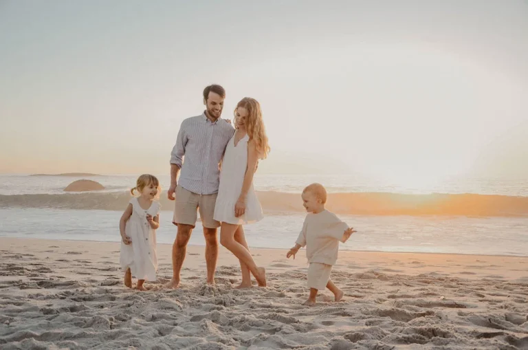 Familie mit zwei Kindern am Strand bei Sonnenuntergang