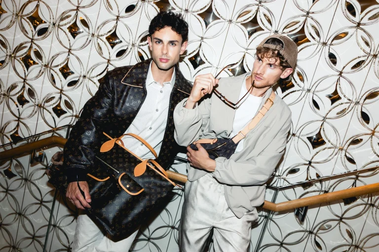 Zwei Männer präsentieren Louis-Vuitton-Taschen vor Spiegelwand