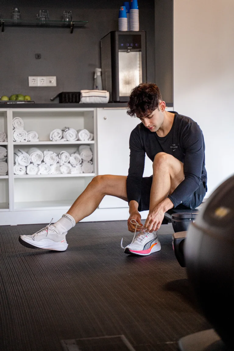 Mann bindet Sportschuhe im Fitnessstudio