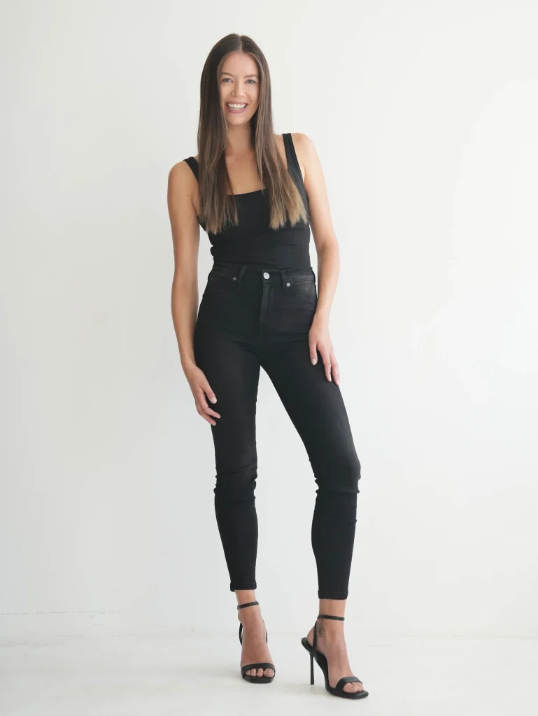 Lächelnde Frau in schwarzem Top und Jeans