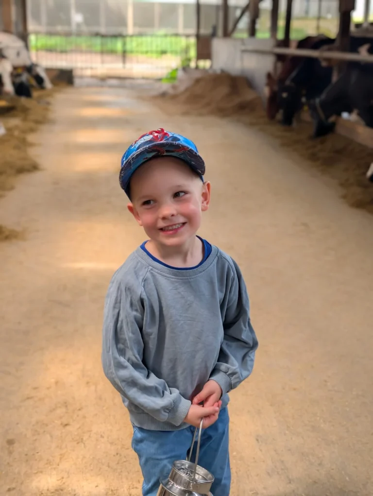 Junge im Stall mit kleinem Milcheimer
