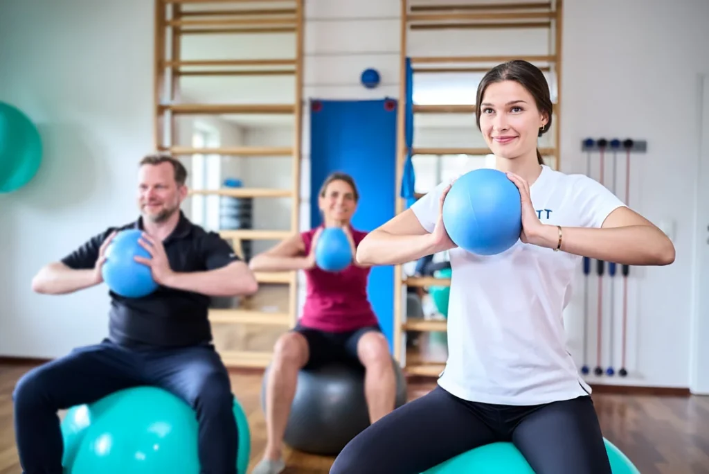 Drei Personen trainieren mit Medizinbällen im Fitnessstudio