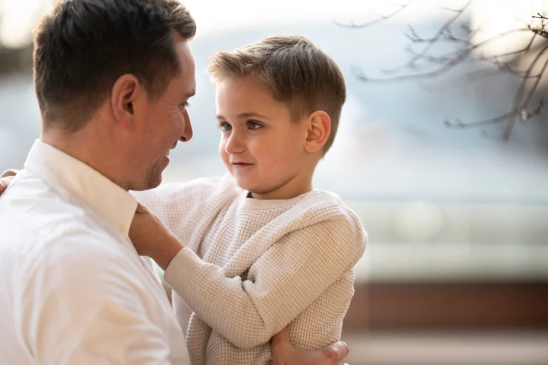 Vater hält Sohn im Arm und lächelt
