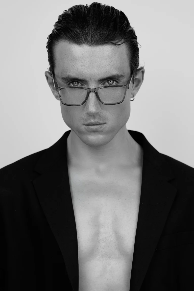 Schwarzweiß-Porträt einer Person mit Brille und Blazer