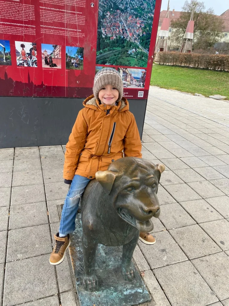 Kind sitzt auf Bronze-Statue im Park