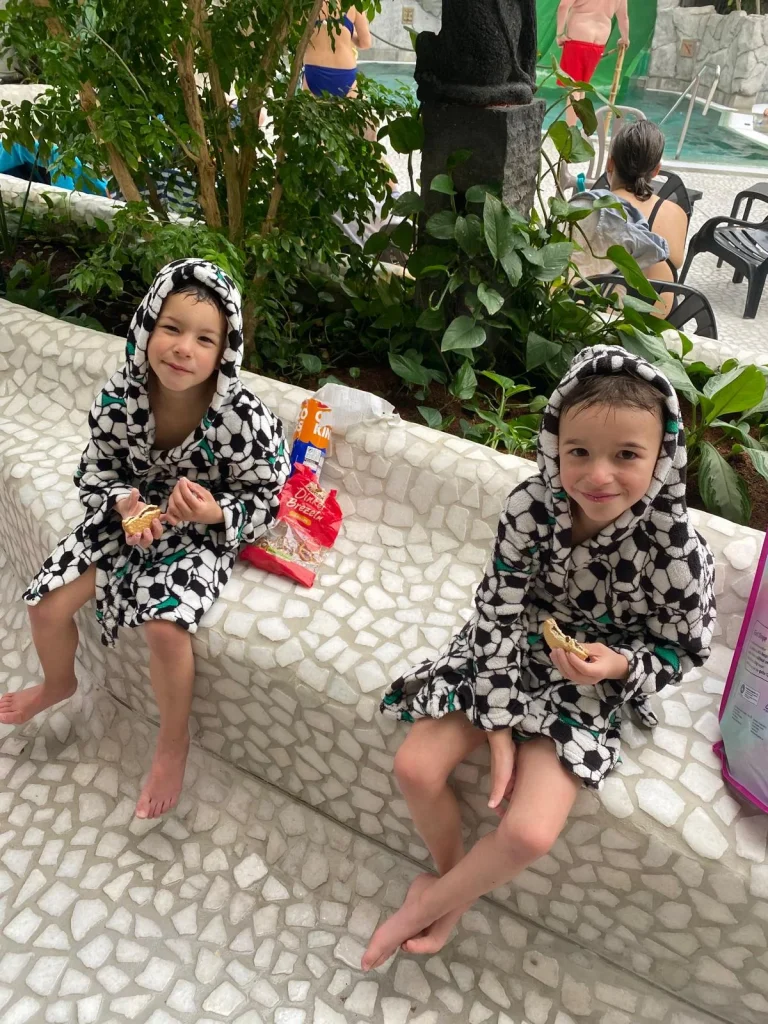 Zwei Kinder im Bademantel am Pool