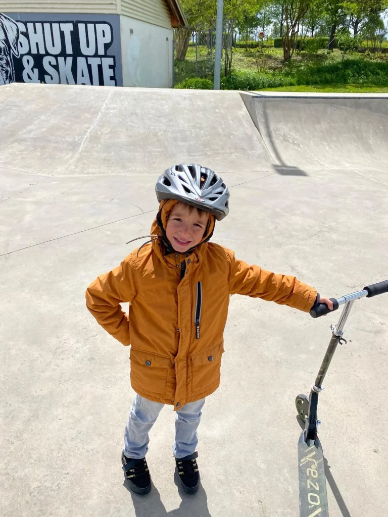 Kind mit Helm und Roller im Skatepark