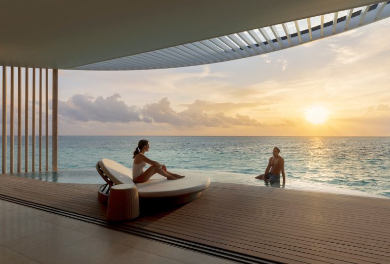 Paar am Infinity-Pool mit Meerblick bei Sonnenuntergang