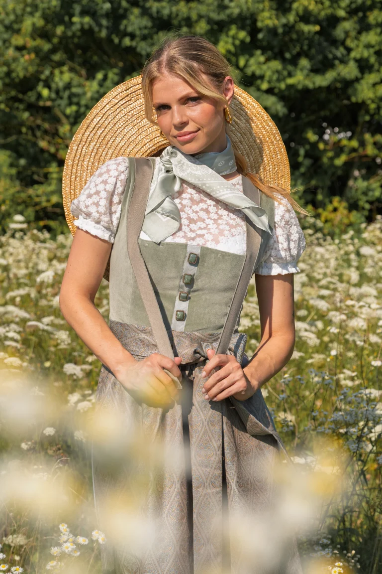 Frau im Dirndl mit Strohhut auf Blumenwiese