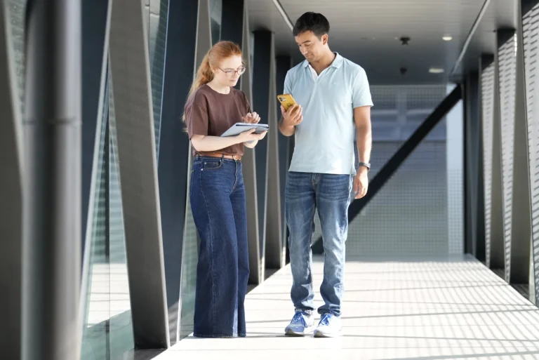 Zwei Personen mit Tablet und Smartphone im Flur