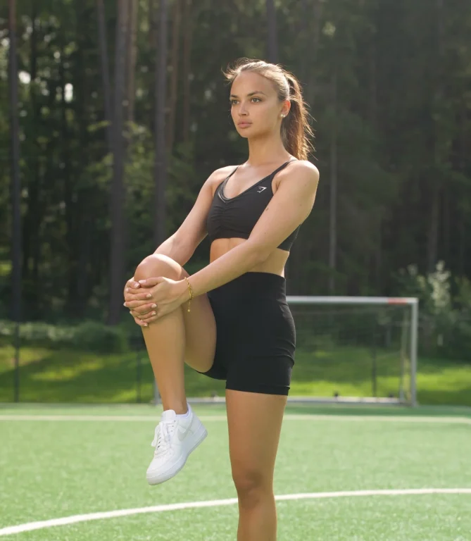 Sportlerin dehnt ihr Knie auf einem Fußballplatz