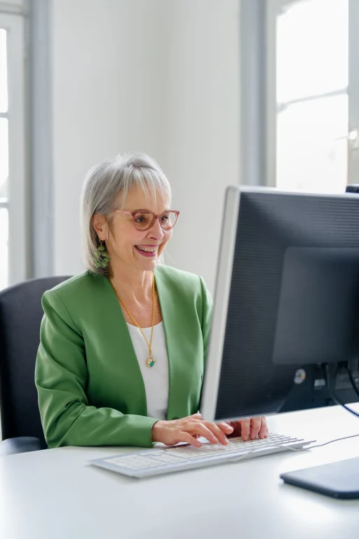 Lächelnde ältere Frau arbeitet am Computer im Büro
