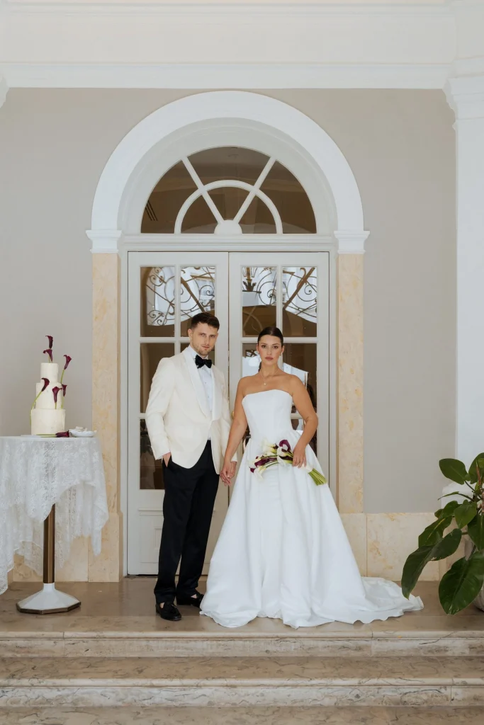 Brautpaar vor eleganter Tür mit Hochzeitstorte