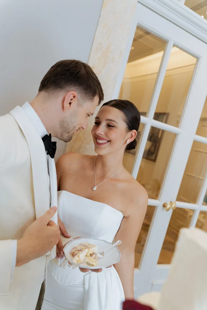 Braut und Bräutigam teilen Hochzeitstorte und lächeln sich an