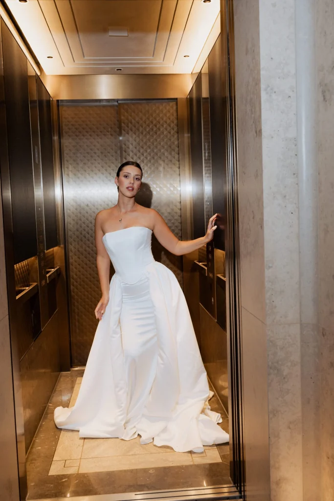 Frau im weißen Abendkleid steht in elegantem Aufzug