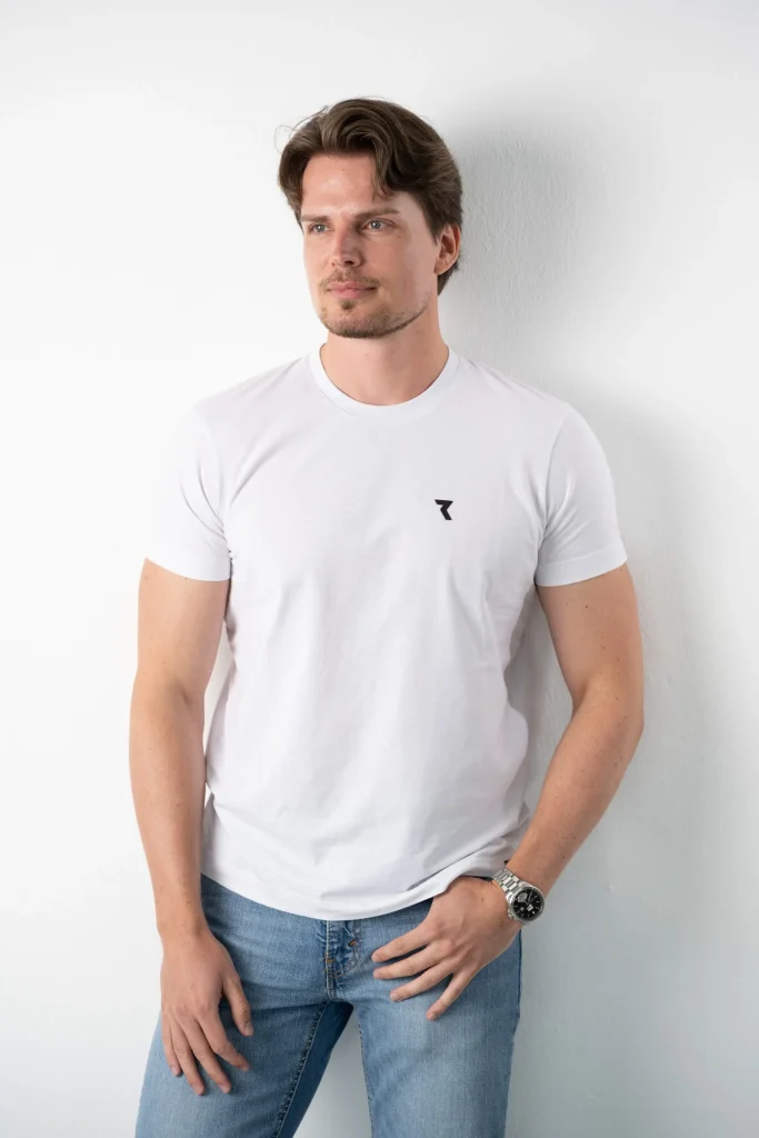 Mann im weißen T-Shirt und Jeans vor weißer Wand