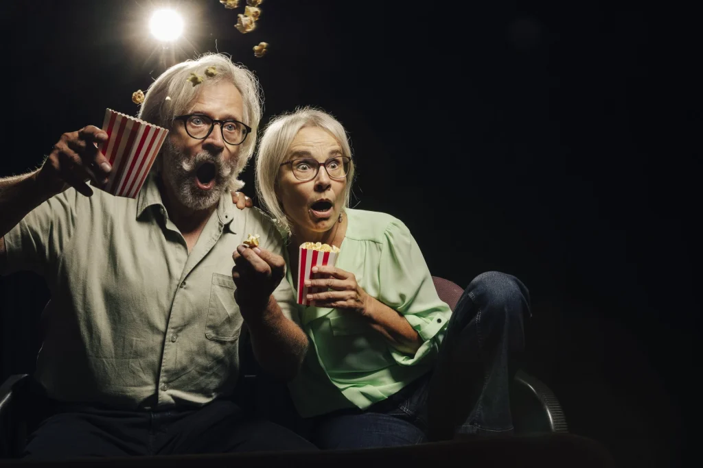 Überraschtes älteres Paar mit Popcorn im Kino