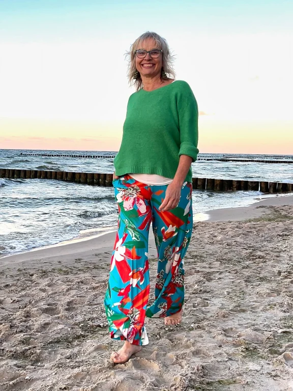 Lächelnde Frau barfuß am Strand bei Sonnenuntergang