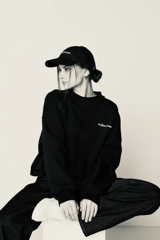 Frau in schwarzem Sweatshirt und Cap sitzt lässig
