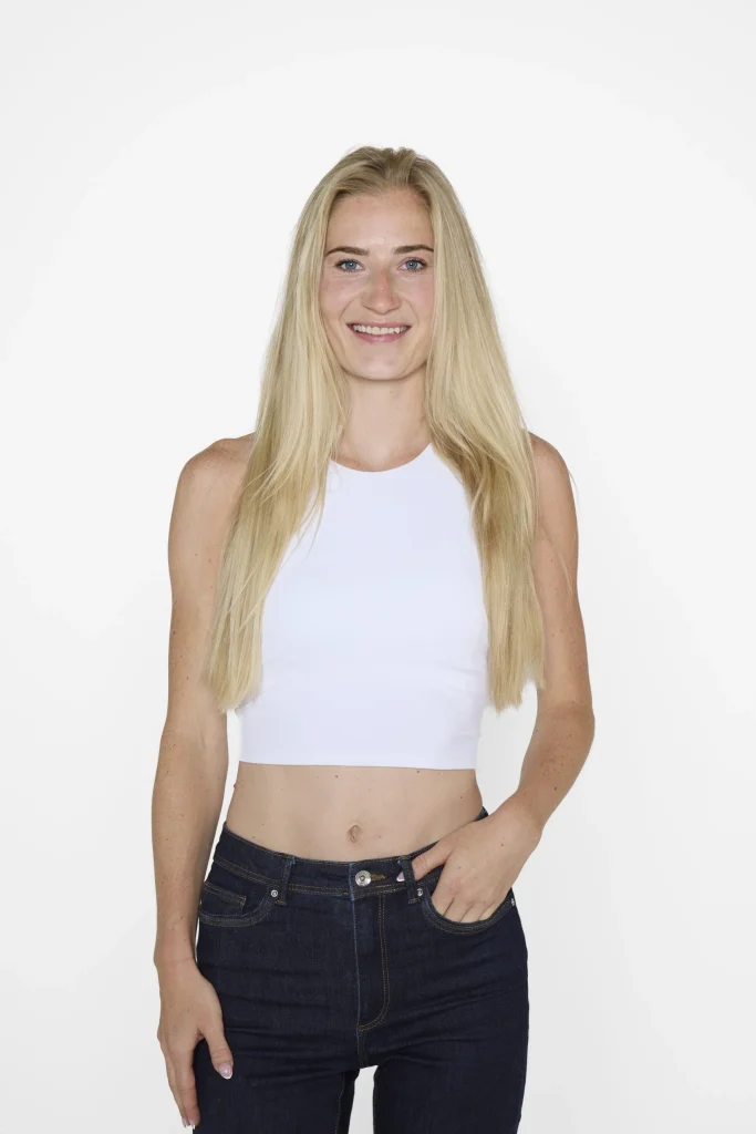 Lächelnde blonde Frau im weißen Crop-Top und Jeans