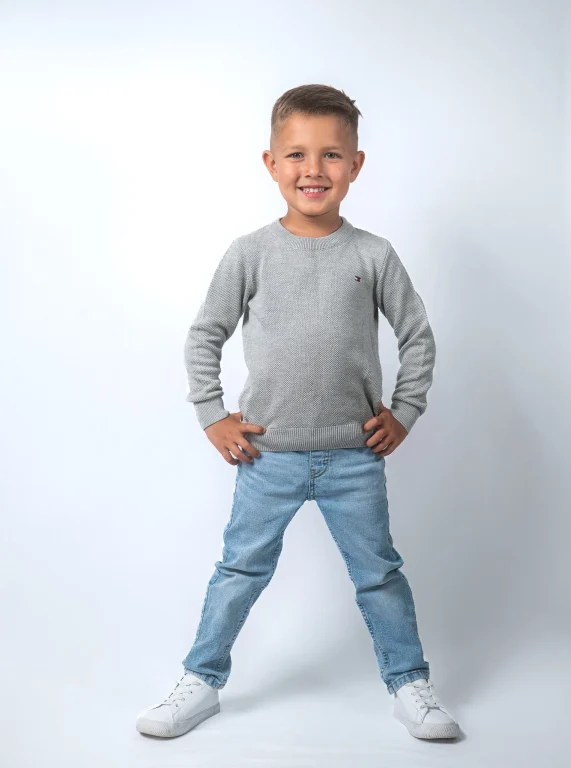 Lächelnder Junge im grauen Pullover und Jeans