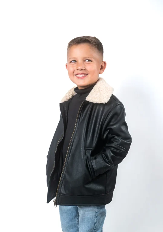 Lächelnder Junge in schwarzer Lederjacke mit Teddykragen