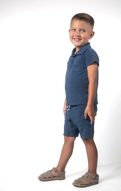 Lächelnder Junge in blauem Polohemd und Shorts