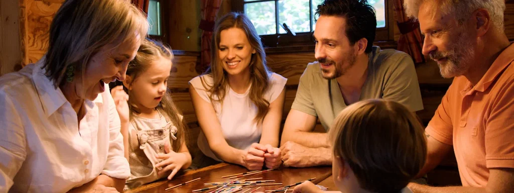 Familie spielt gemeinsam Karten in gemütlicher Holzhütte