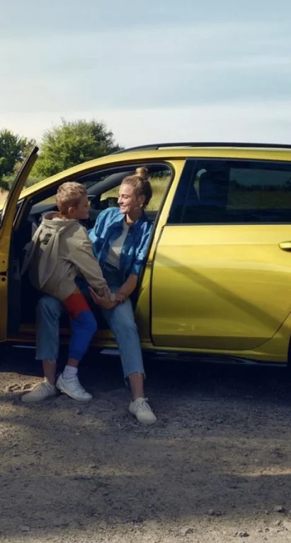 Frau und Junge sitzen an gelbem Auto