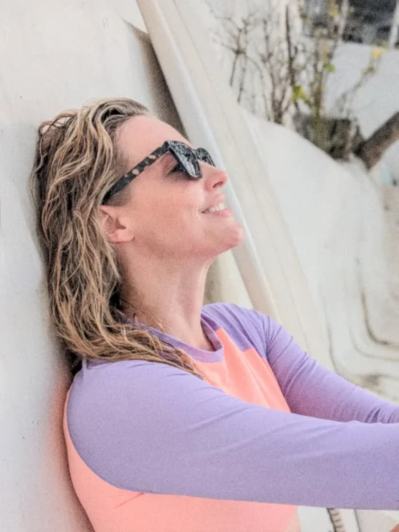 Lächelnde Frau mit Sonnenbrille an weißer Wand