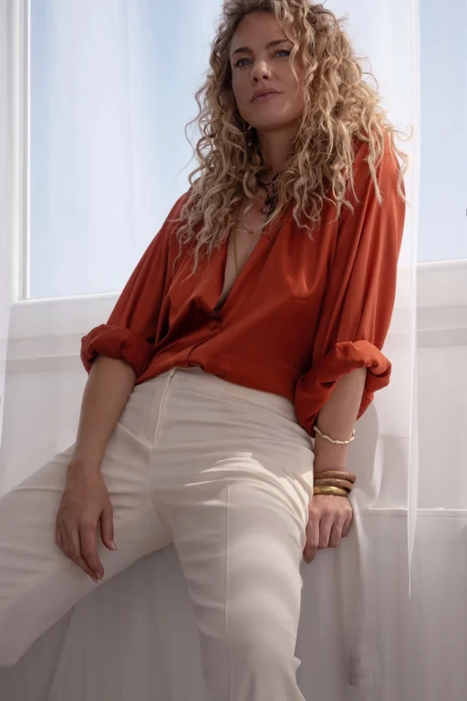 Frau mit Locken in roter Bluse auf weißer Treppe