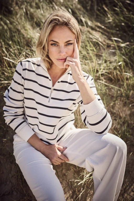 Blonde Frau sitzt nachdenklich zwischen sonnigen Gräsern