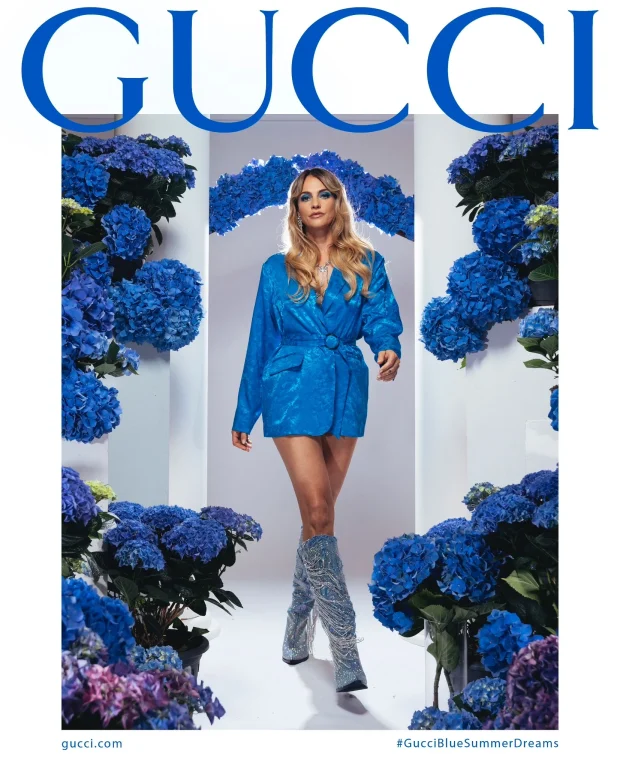Frau im blauen Gucci-Anzug zwischen blauen Hortensien