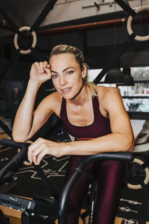 Frau pausiert lächelnd auf einem Trainingsrad im Fitnessstudio